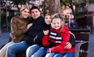 Average family with two kids sitting on bench outdoors
