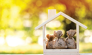 wooden house cut out with three bags of money inside