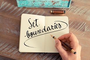Person’s hand writing “Set boundaries” in a notebook with a fountain pen
