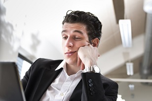 male business employee is bored in front of his computer, shows lack of engagement, commitment to job