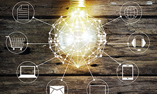 a bright lightbulb overlaid with icons representing digital delivery channels, hanging in front of a wood background