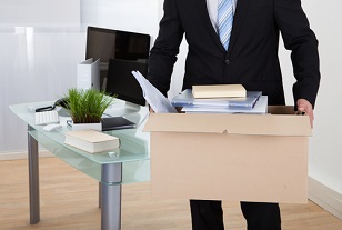 Fired employee carrying a box of his belongings away from the office