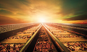 train tracks converging in front of a sunset sky
