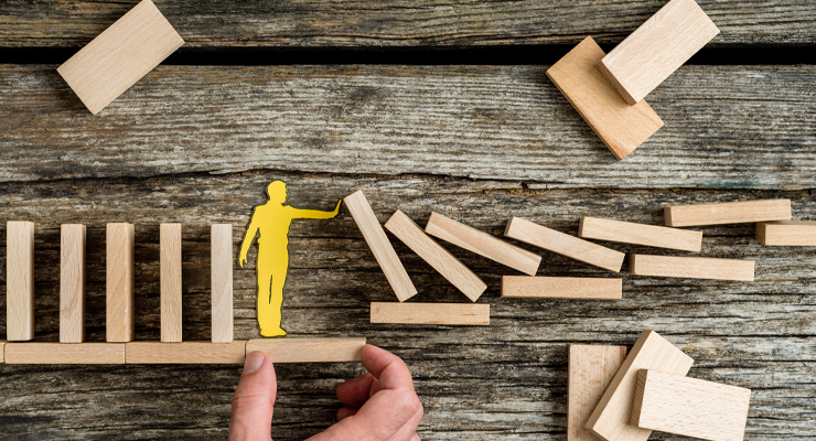 Person stopping dominoes from falling