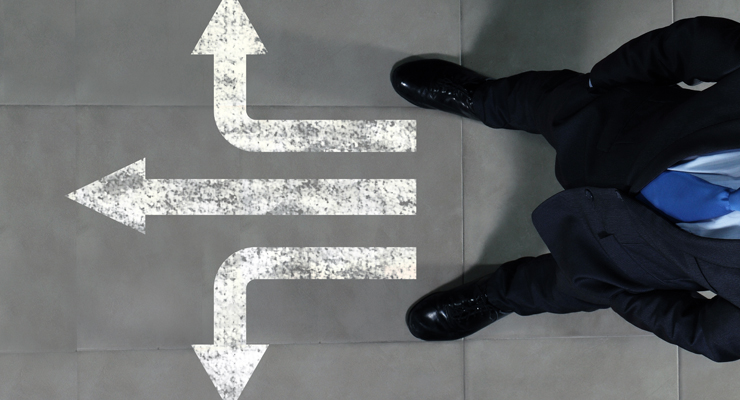 Person in suit looking at multiple paths on the ground