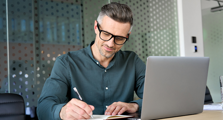 Man on computer and taking notes learning