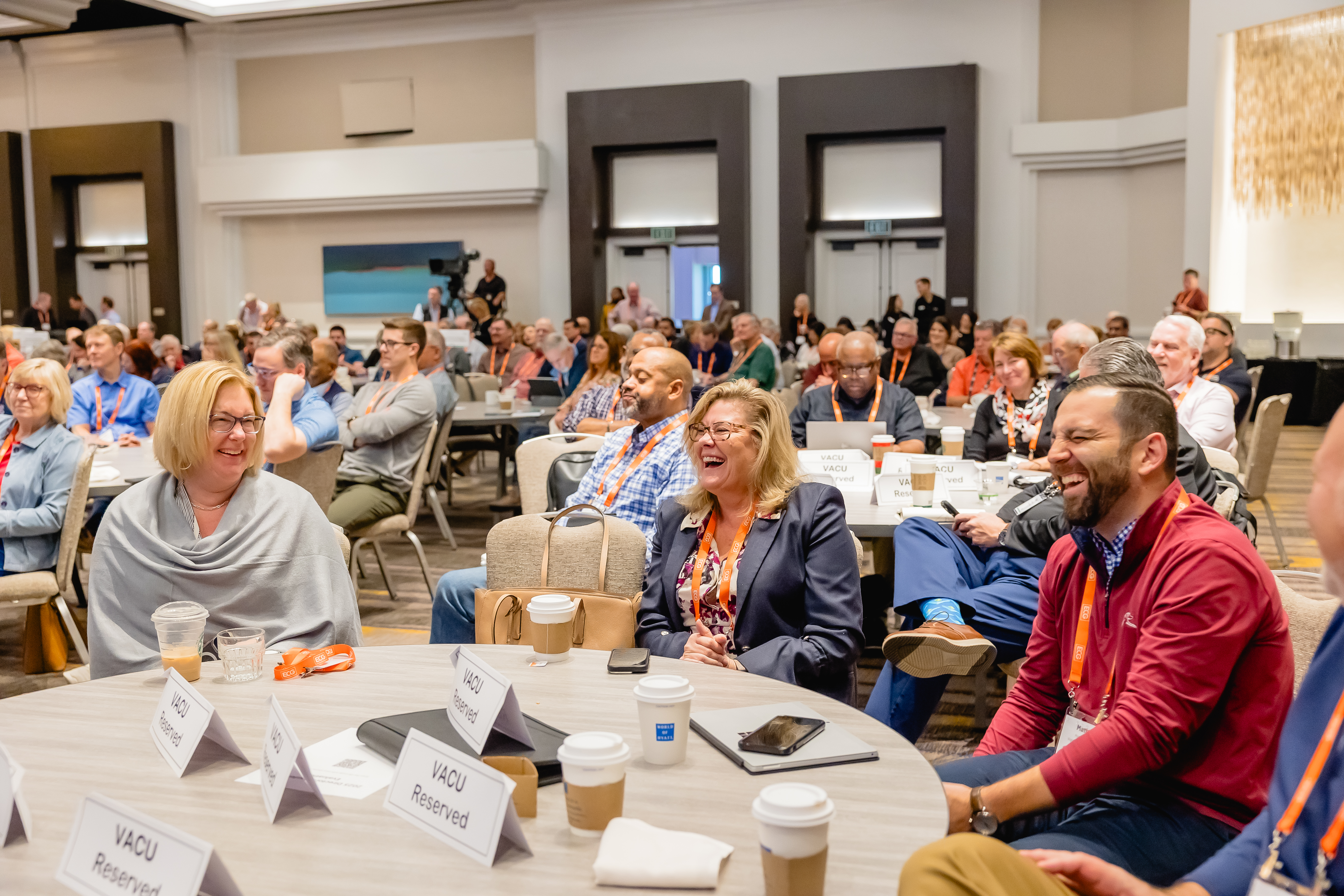 Attendees laughing at table during talk at conference