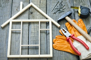 model wood frame of a house with tools lying next to it on a wood table