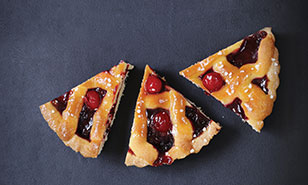 three pieces of cherry pie on a gray backdrop, one slightly smaller than the other two